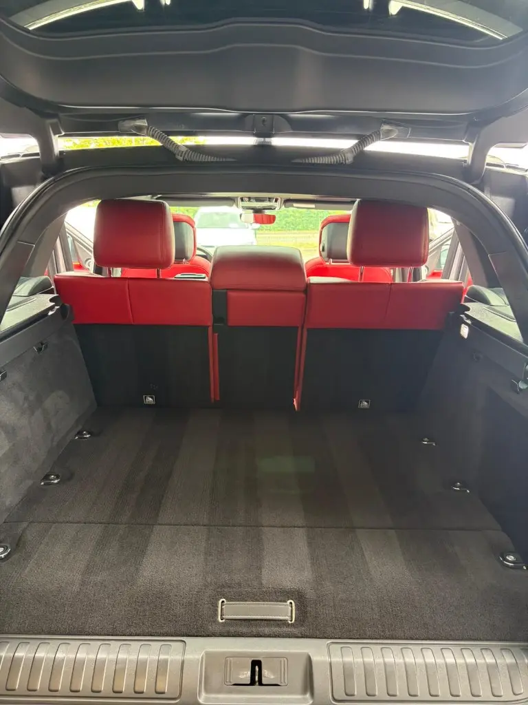 Coffre d'un Range Rover après nettoyage intérieur, moquette aspirée et sièges arrière en cuir rouge