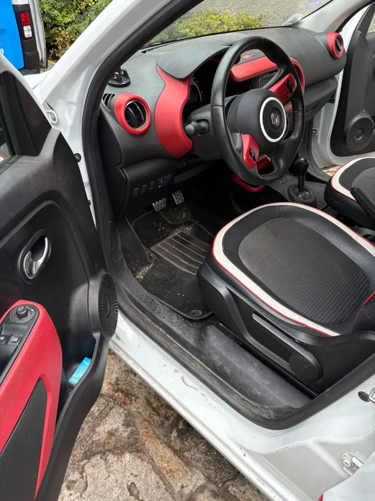 Poste de conduite Renault Twingo avant nettoyage : pédalier poussiéreux, moquette et seuil de porte sales